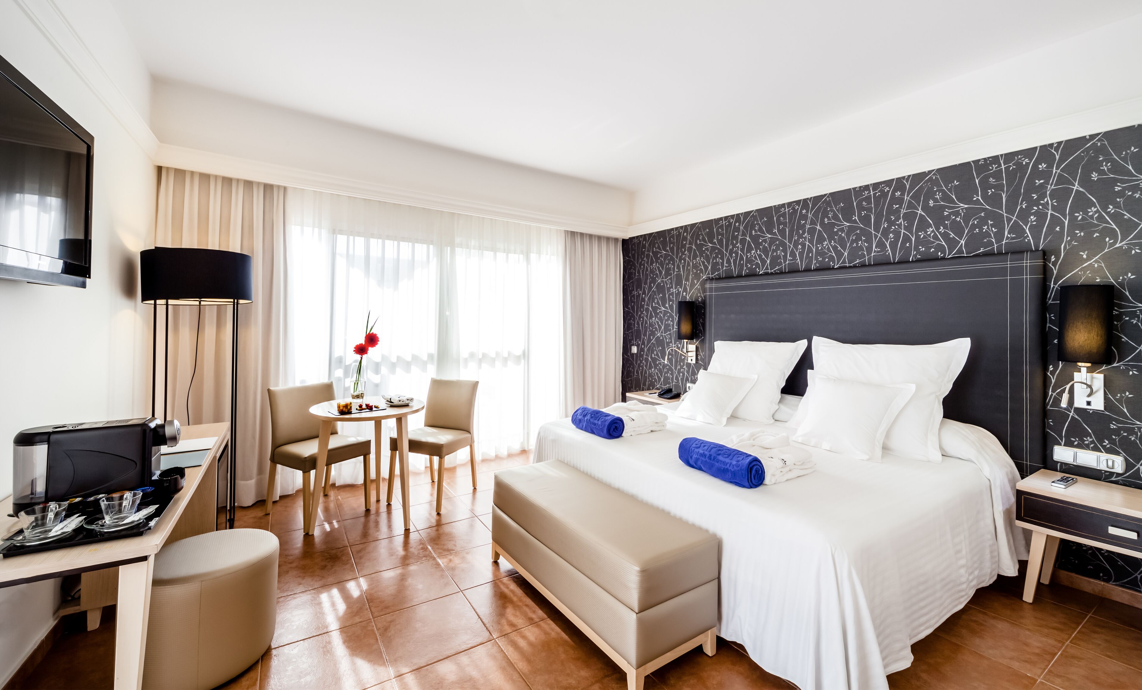 Ein Hotelzimmer mit Bett, Nachttisch, Schreibtisch, Stuhl und Fernseher.