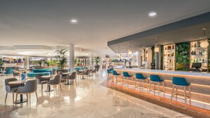 Un espace bar moderne doté d’un comptoir en marbre et de tabourets de bar bleus.