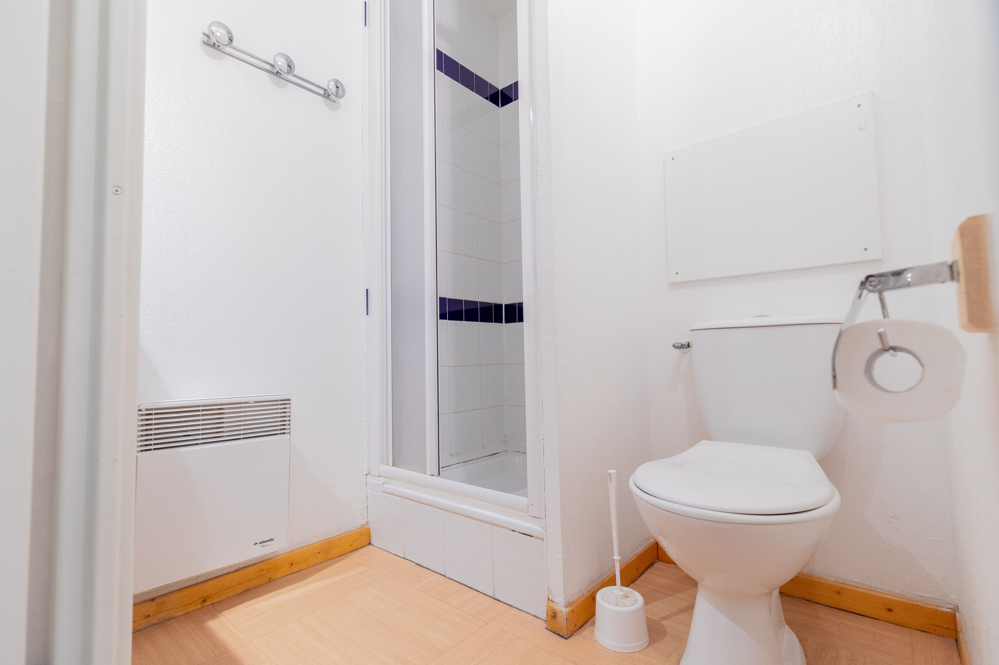 A bathroom with a white toilet, a shower enclosure, and a white sink.