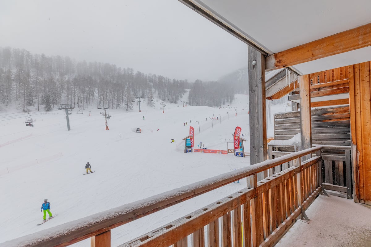 A snowy ski slope with a wooden balcony overlooking the area.