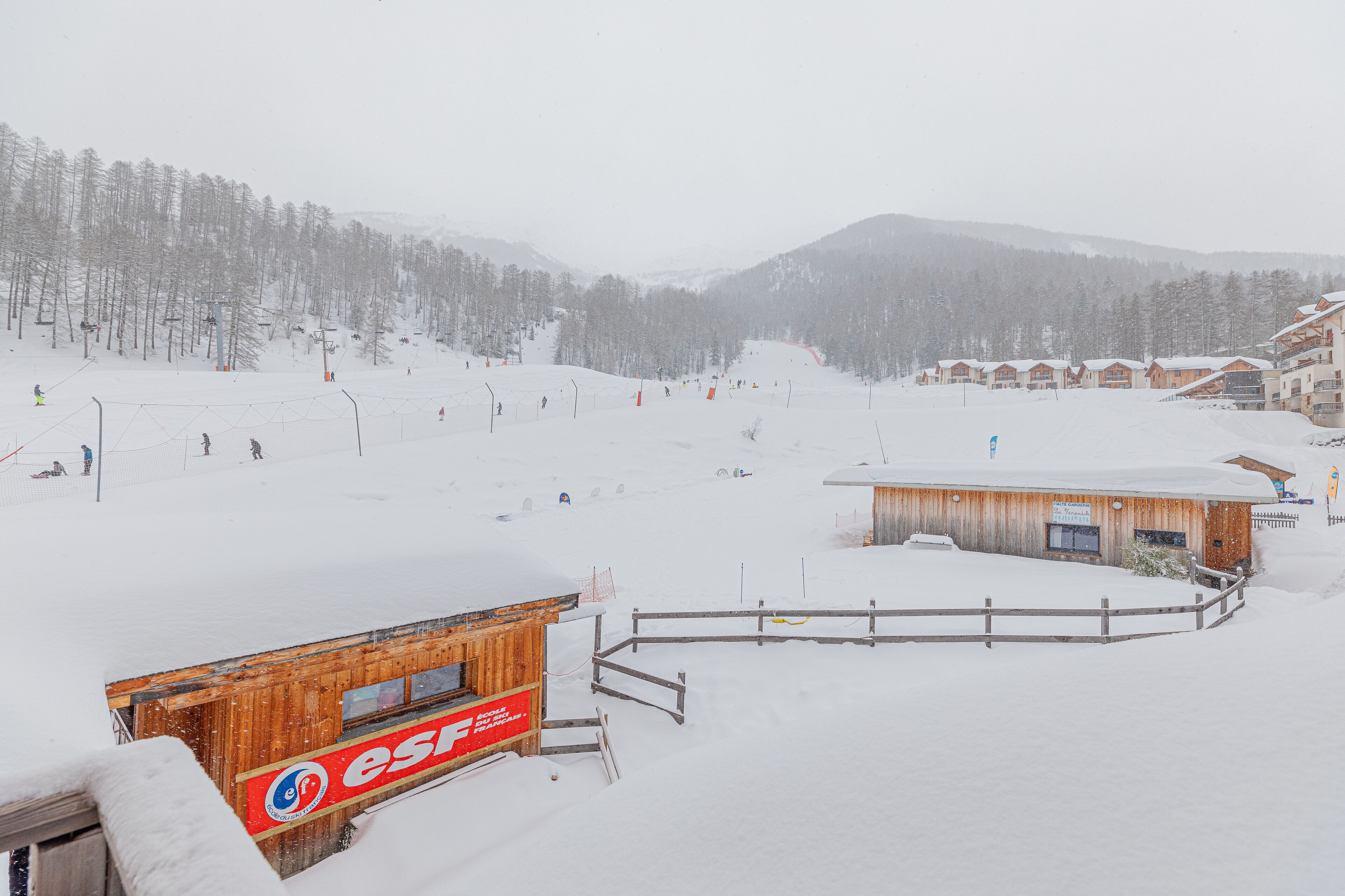 A snowy ski resort with wooden buildings, including a restaurant named 'esf'.