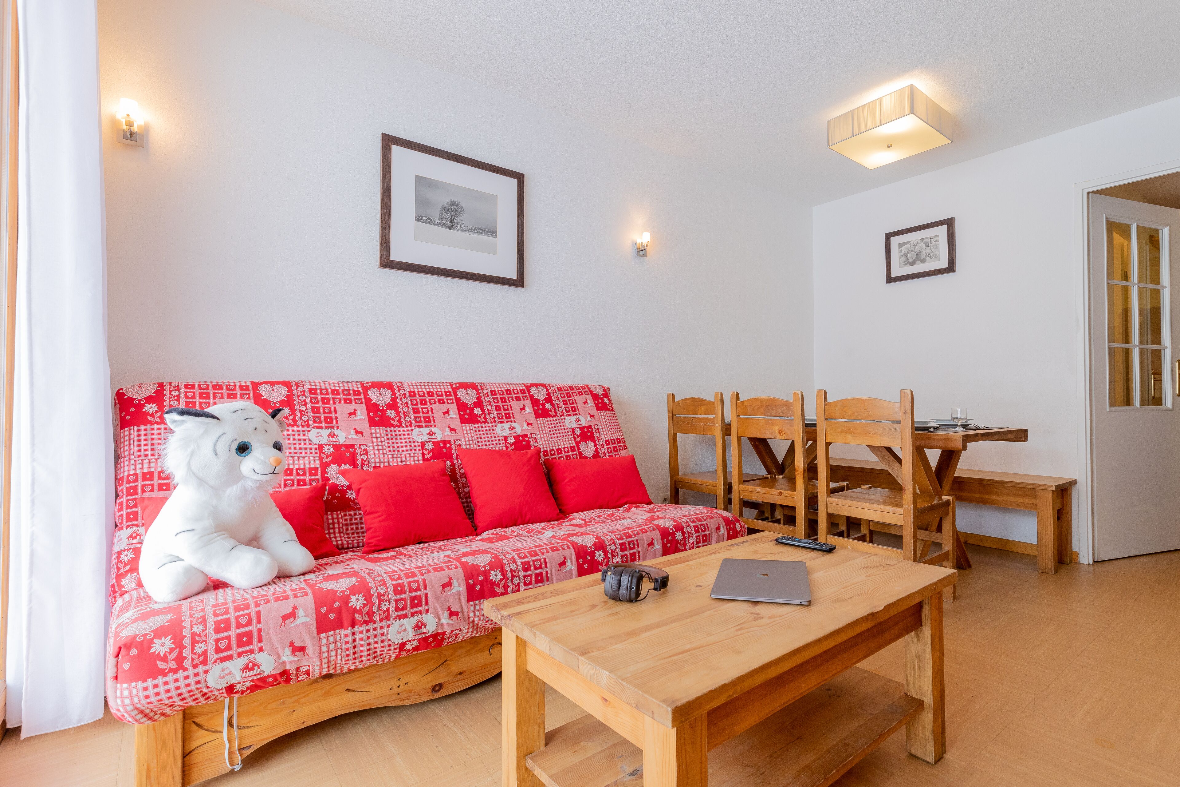 Een gezellige kamer met een rode gestreepte bank, een houten tafel en een houten eethoek.