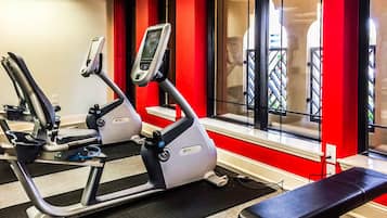 Une salle de sport équipée de matériel d’exercice, d’un banc et d’une fenêtre donnant sur un balcon.