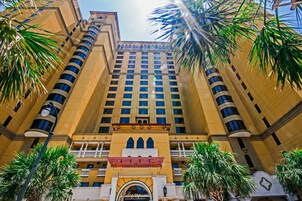 A tall, multi-story hotel with a symmetrical facade, featuring balconies and a central entrance with an archway.
