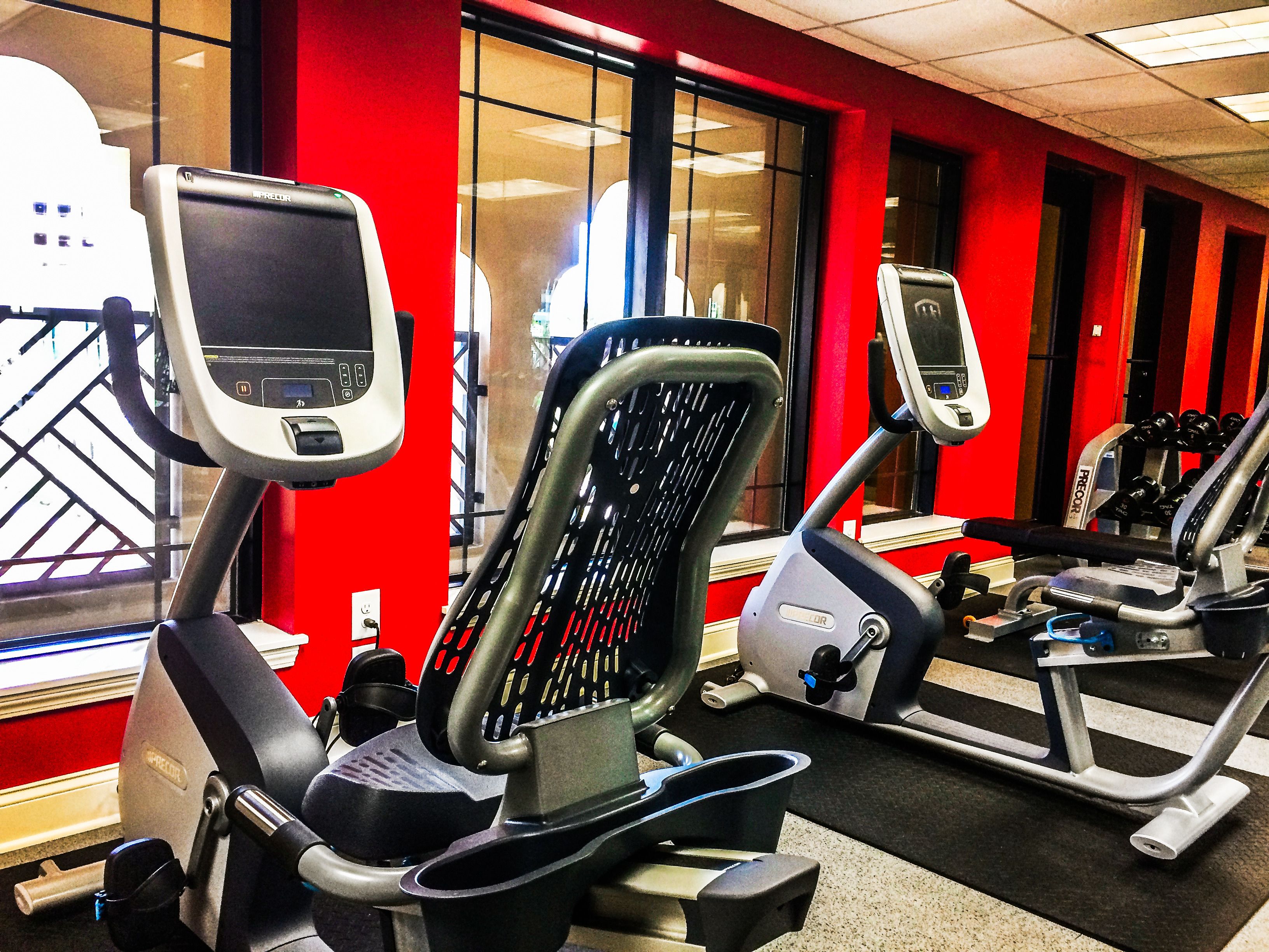 A gym with exercise equipment and red walls.
