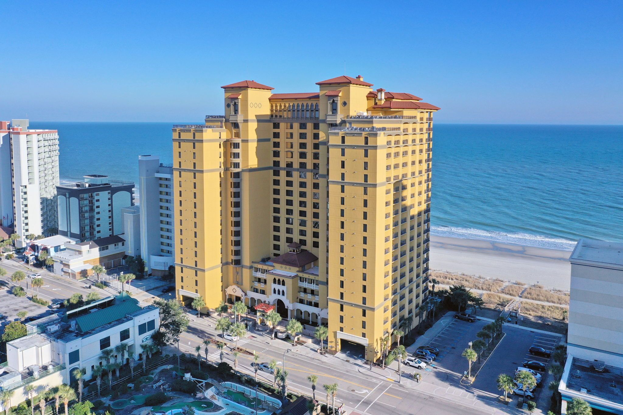 Un hôtel de grande hauteur doté de nombreux balcons, situé près d’une plage et offrant une vue dégagée sur l’océan.