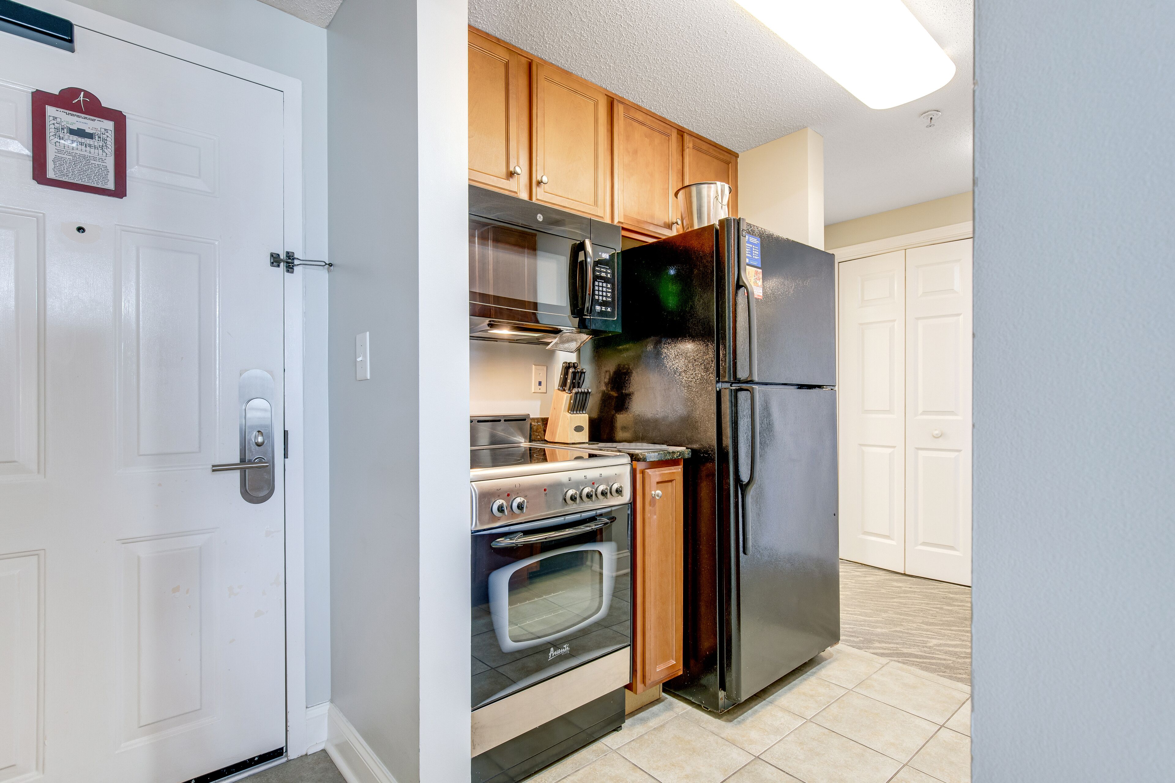 A kitchen with wooden cabinets, a stainless steel refrigerator, a microwave, an oven, and a toaster.