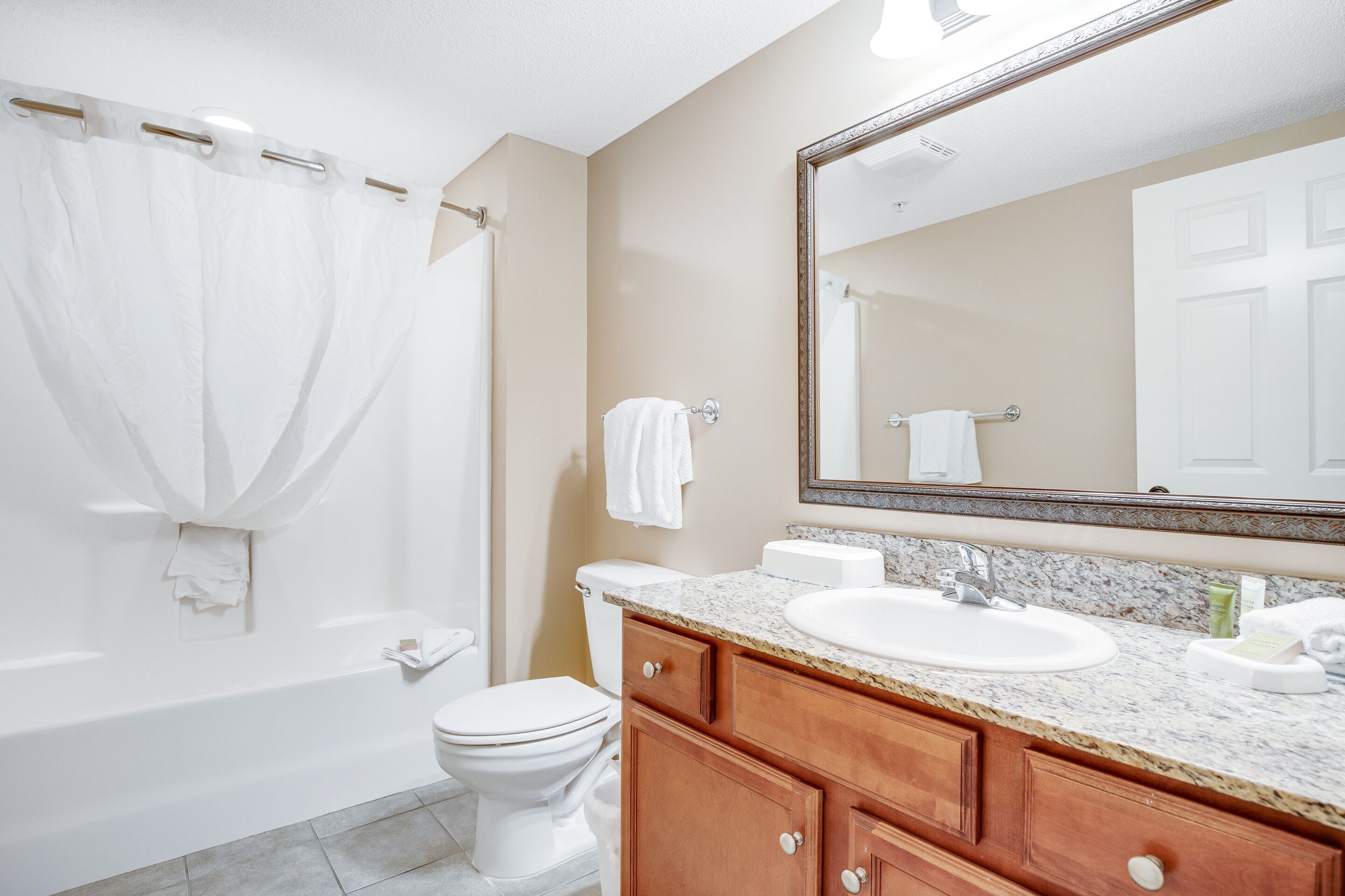A bathroom with a bathtub, toilet, sink, and vanity with drawers and a mirror.