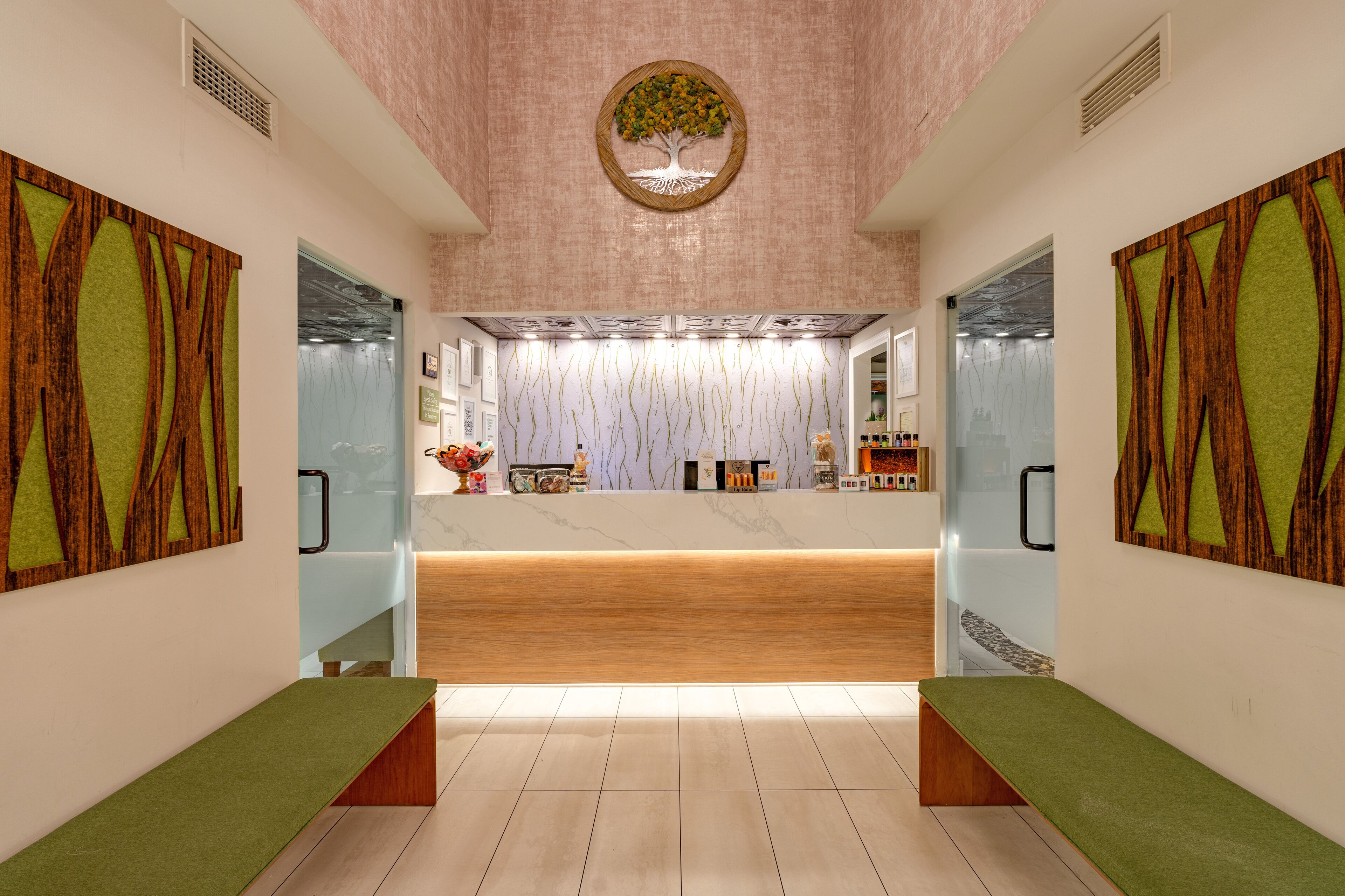 A modern reception area with a wooden reception desk, a decorative tree on the ceiling, and a bench on each side.