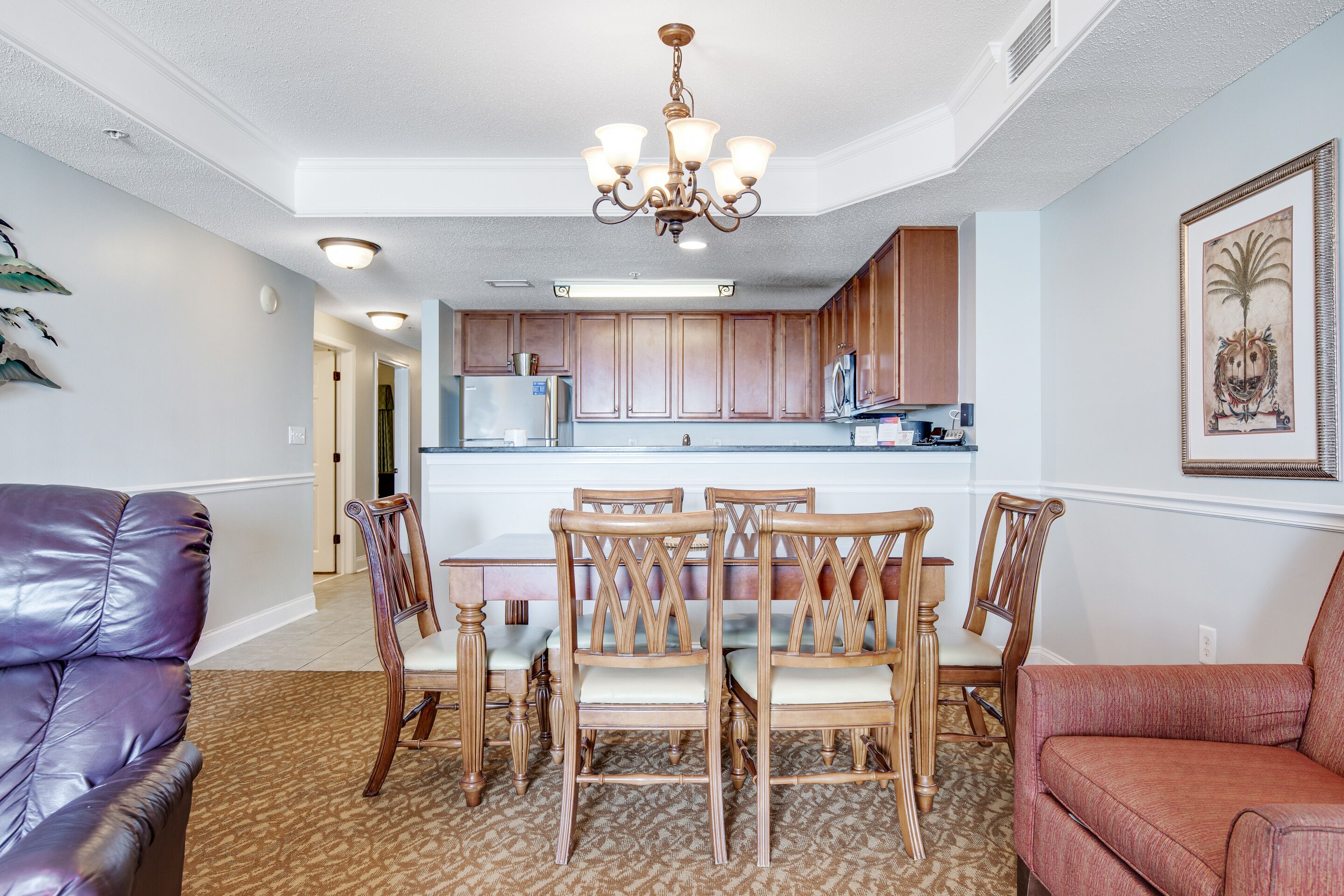 A modern kitchen with wooden cabinets, a central island, and a chandelier.