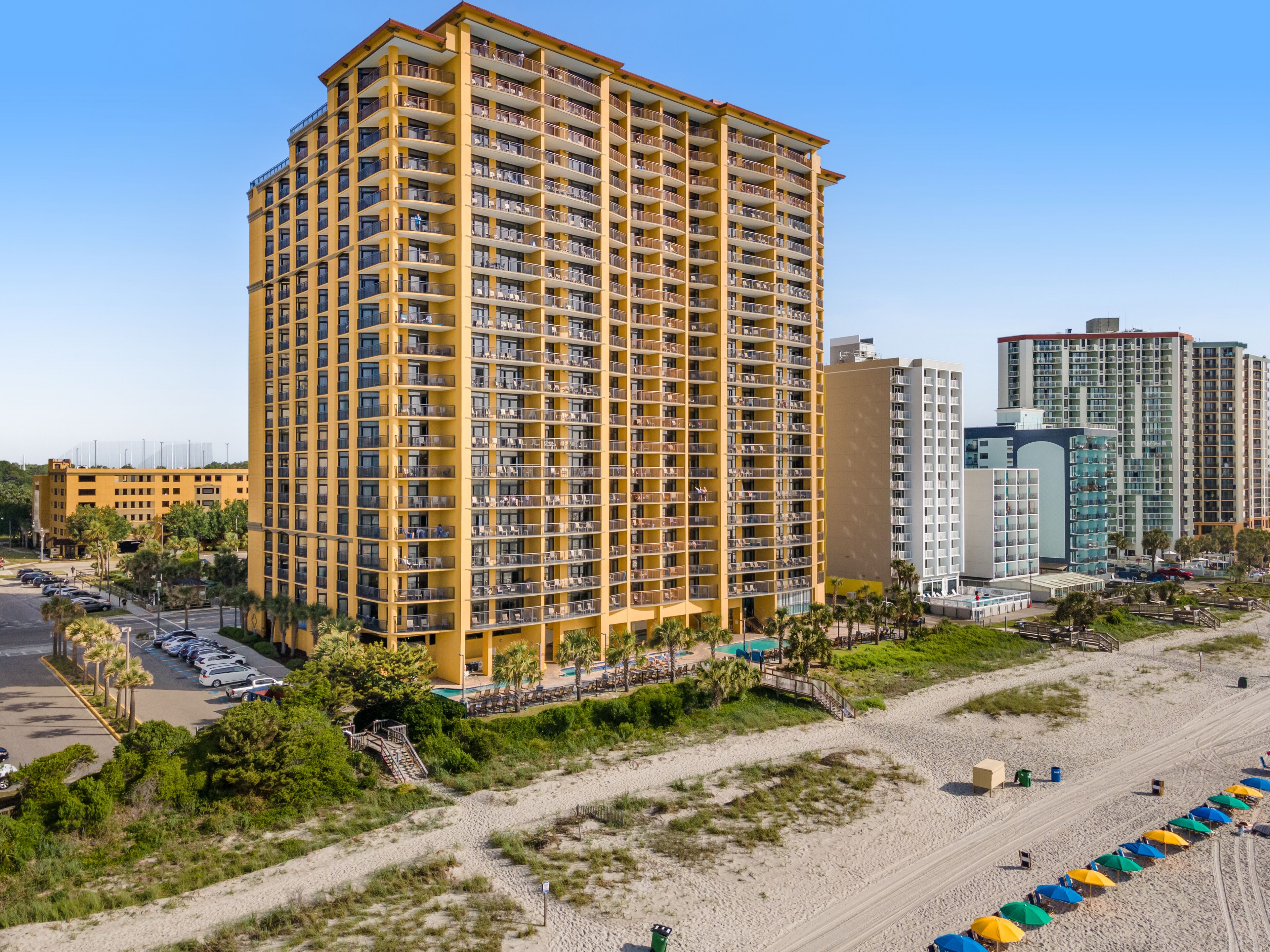 Un hôtel de grande hauteur doté de nombreux balcons, d’un espace piscine et situé en bord de mer.