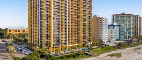 Un hôtel de grande hauteur doté de nombreux balcons, d’un espace piscine et situé en bord de mer.
