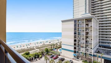 Un hotel con vista a la playa, que cuenta con varios balcones y un estacionamiento con varios coches.