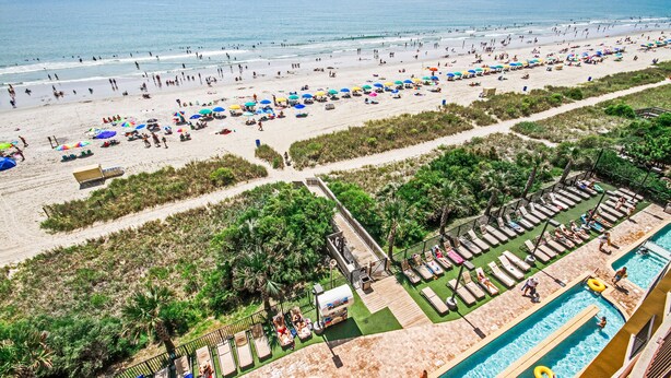 Un complexe hôtelier de bord de mer doté d’une piscine, de chaises longues et de parasols.
