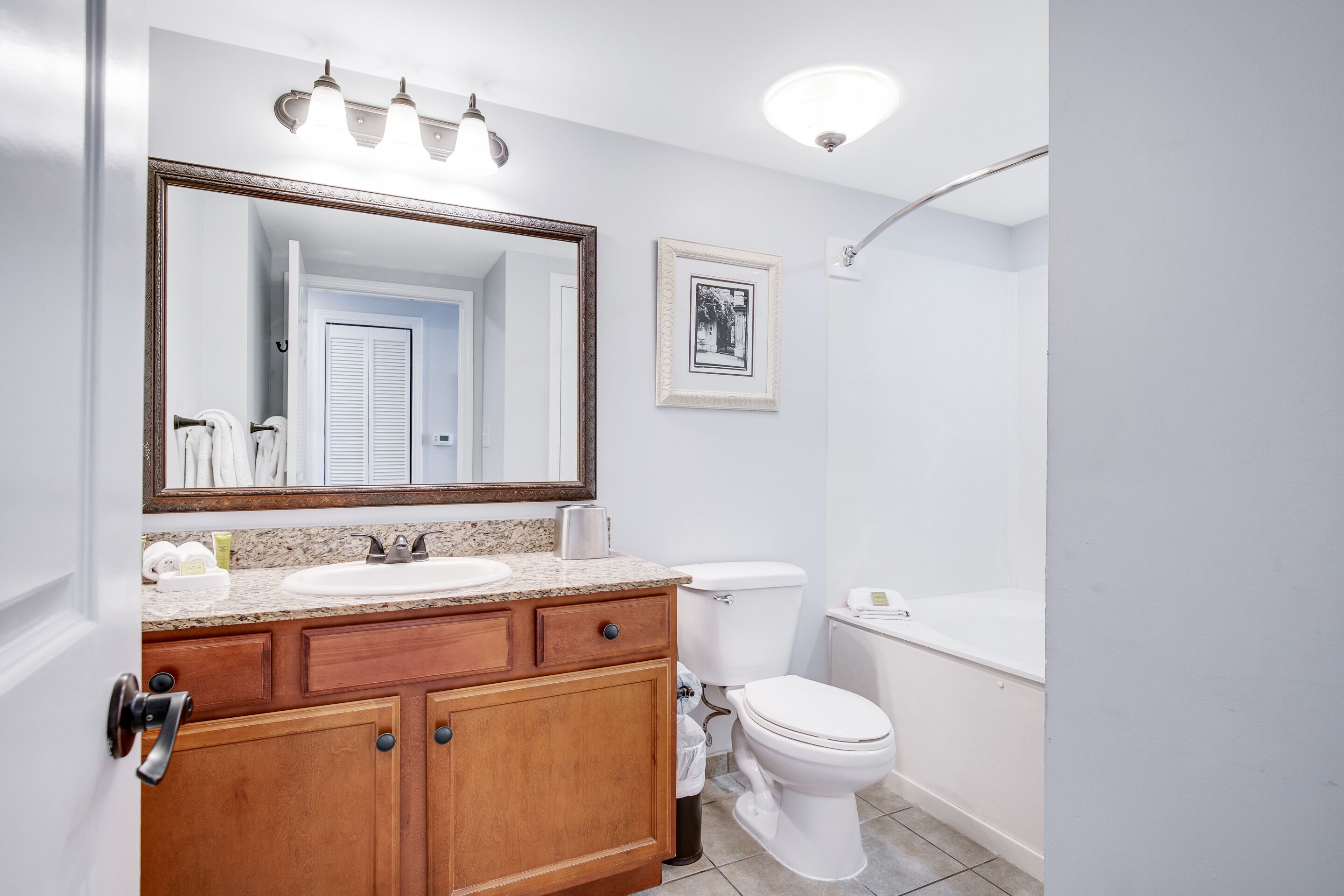 Un baño con tocador de madera, lavamanos blanco y un espejo grande.