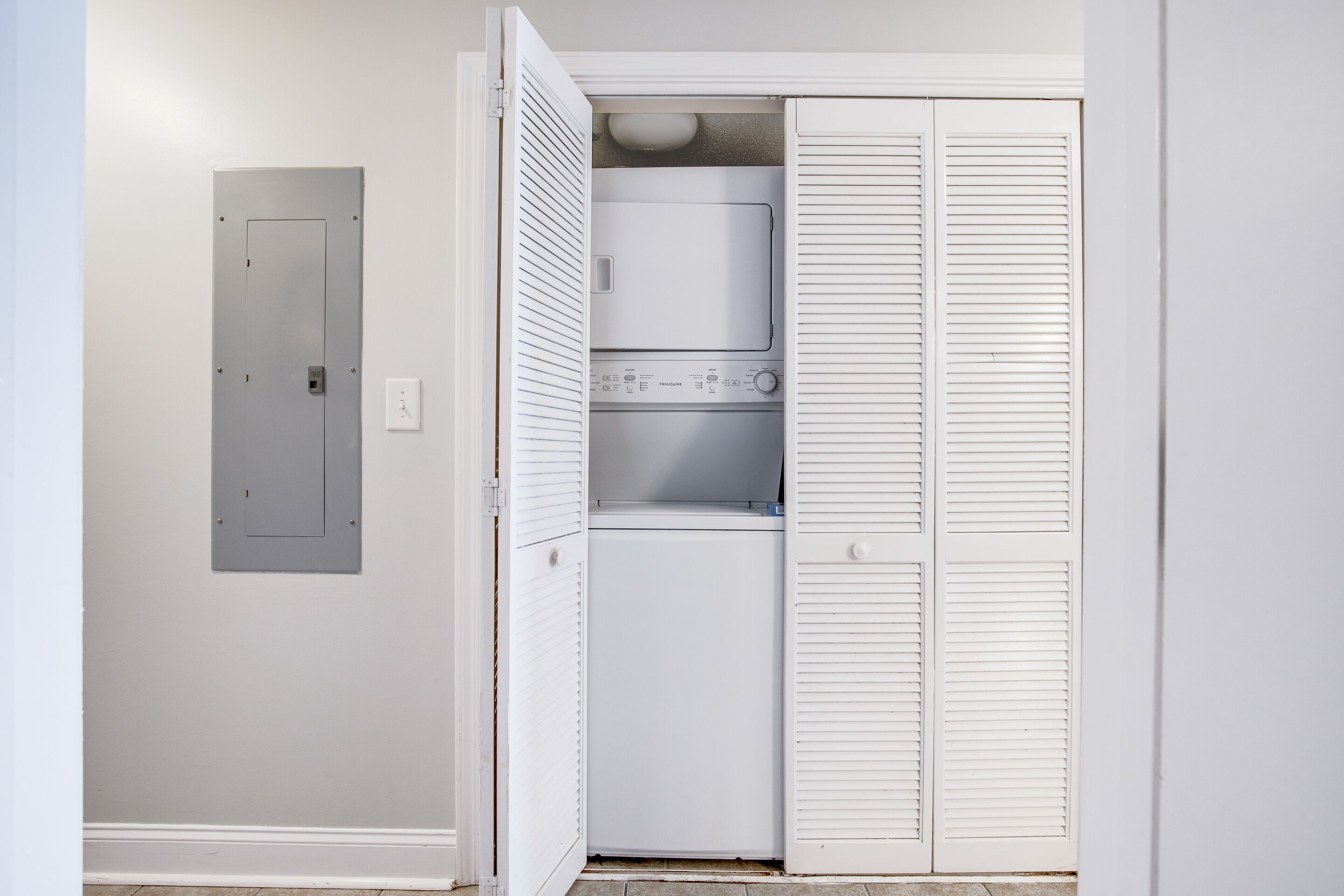 A laundry room with a washer and dryer, a utility door, and a white closet with louvered doors.