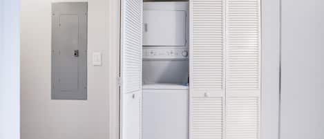 A laundry room with a washer and dryer, a utility door, and a white closet with louvered doors.
