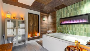 Une salle de bain moderne avec une grande baignoire, un meuble en verre contenant des serviettes et un banc en bois.