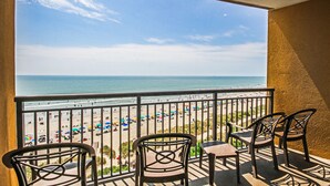 Un balcon avec vue sur une plage et l’océan.