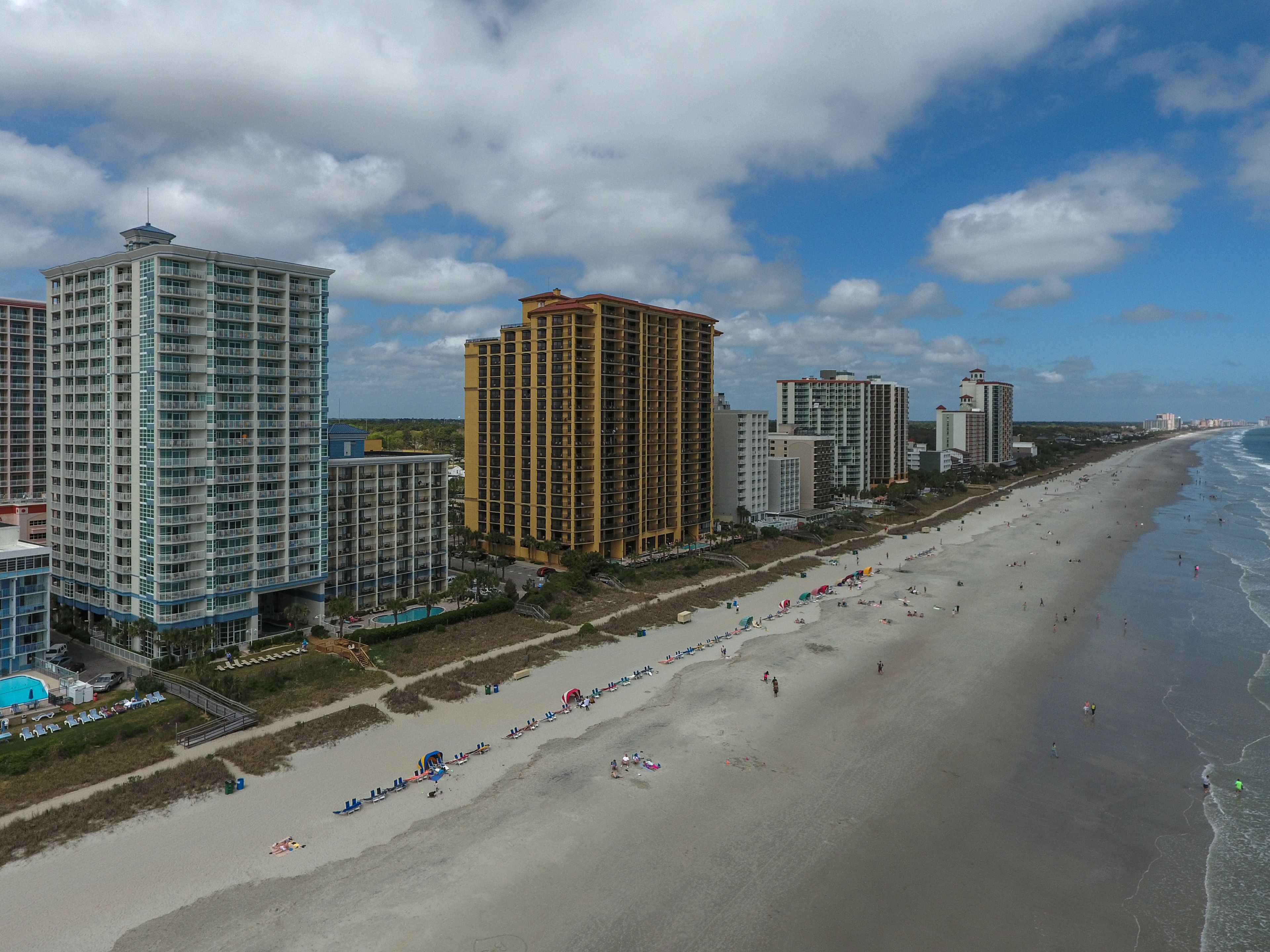 Un paysage urbain côtier avec de hauts immeubles, une plage de sable et un ciel dégagé.