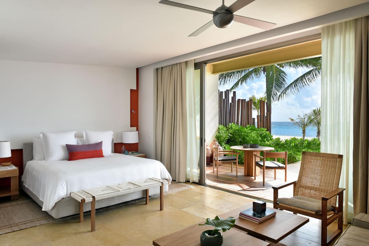 A hotel room with a bed, a desk, a chair, and a view of the ocean.