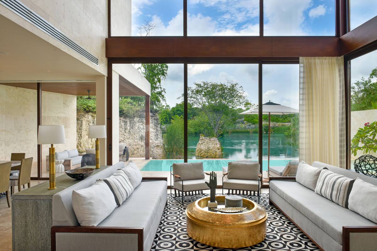 A modern interior with a pool view, featuring a sofa, chairs, and a coffee table.