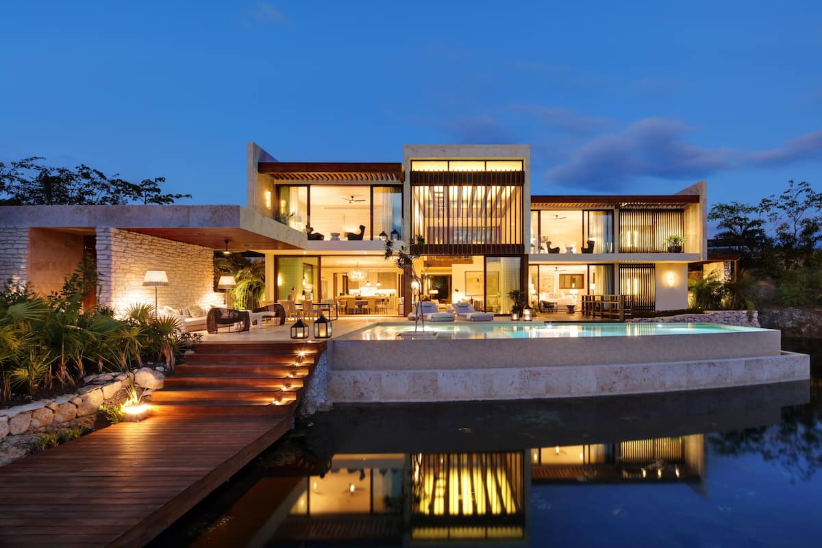 A modern house with a swimming pool, wooden deck, and outdoor seating area.