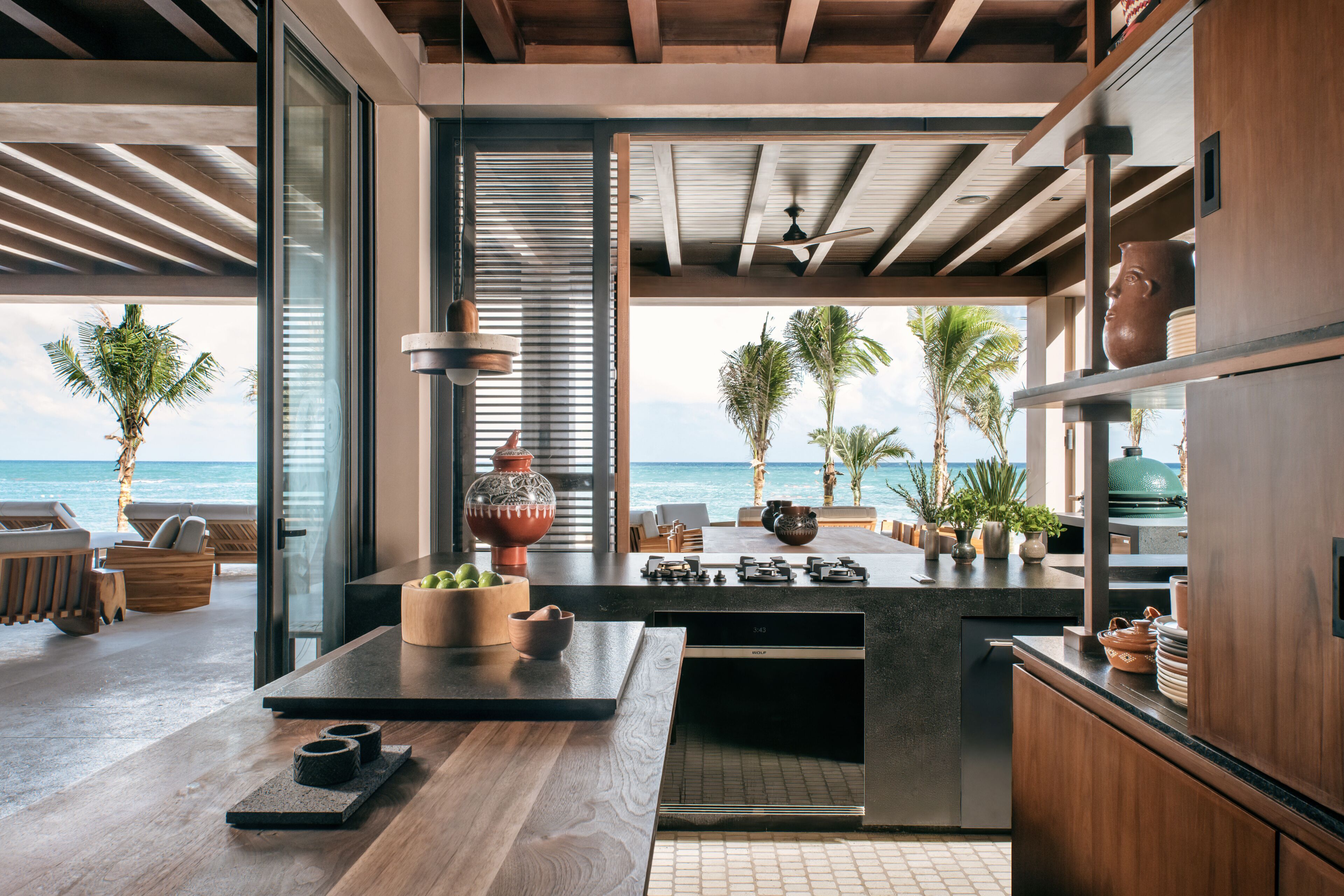 A modern kitchen with a view of the ocean, featuring a wooden countertop, a built-in stove, and various kitchen appliances.