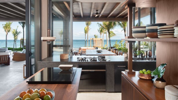 A modern kitchen with a large island, a dining area with a view of the ocean, and a seating area with a view of the beach. - Rosewood Mayakoba (Playa del Carmen)