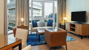 Moderni hotellihuone, jossa on suuri ikkuna, sohva, televisio ja puinen kaappi.