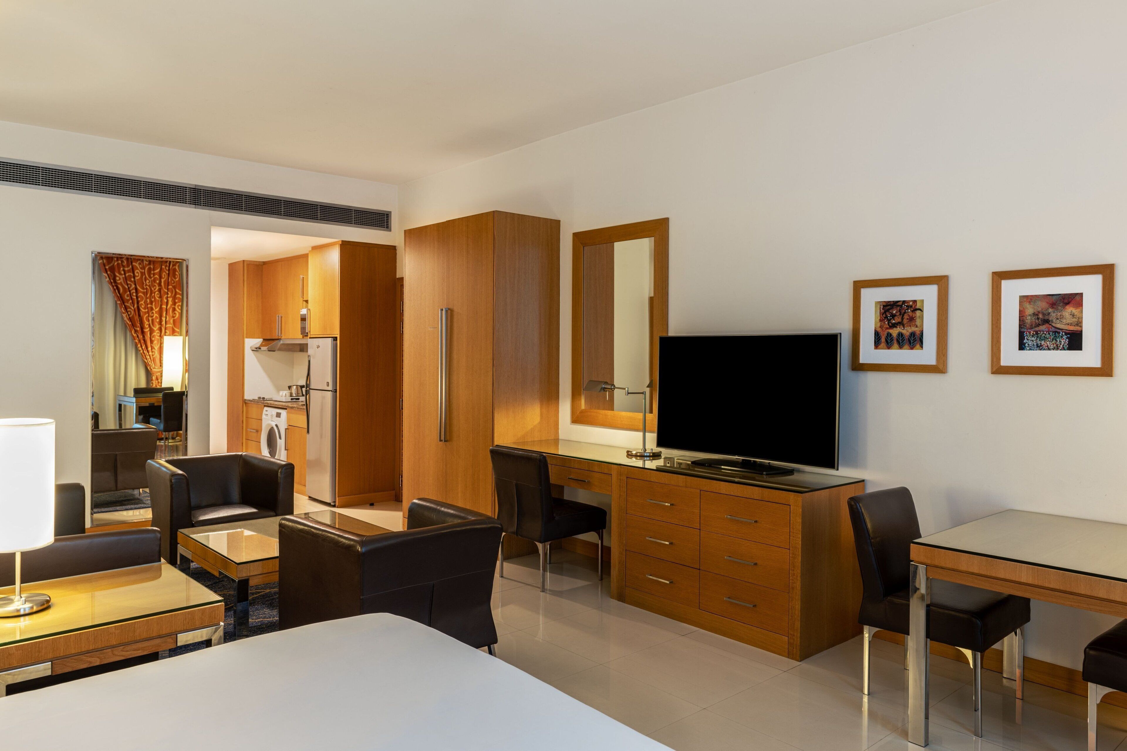 A hotel room with a bed, a desk, a chair, a television, and a wardrobe.