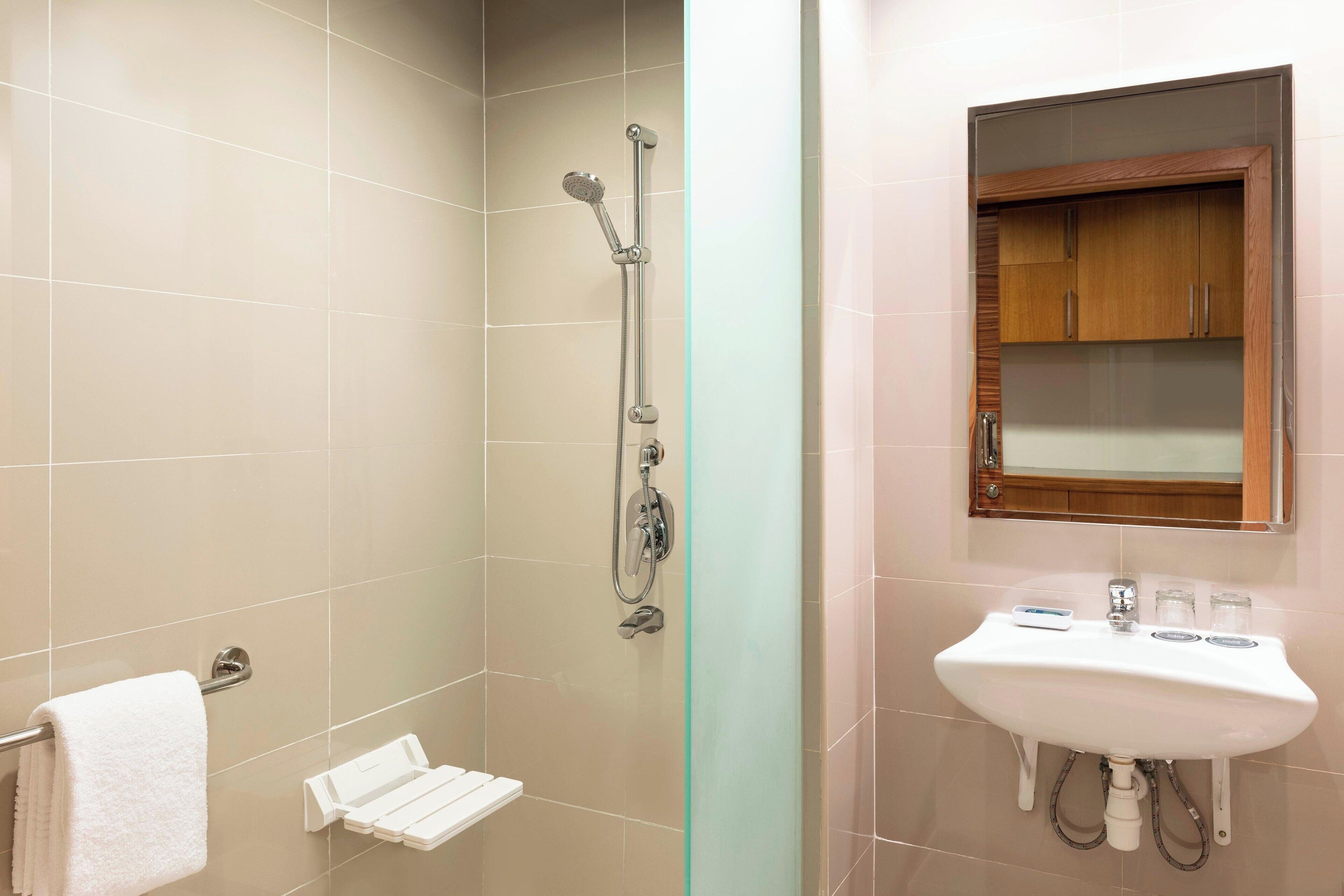 A bathroom with a shower, a sink, and a mirror.