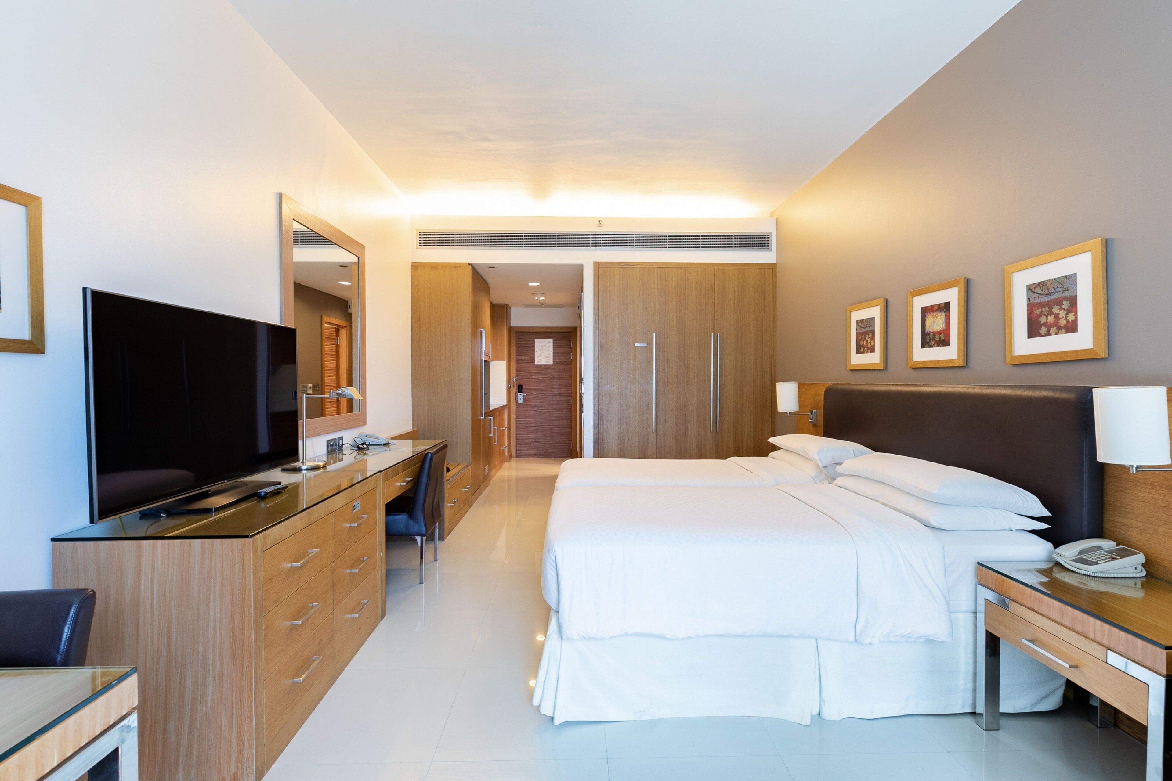 Una habitación de hotel moderna con cama, escritorio, televisión y armario.