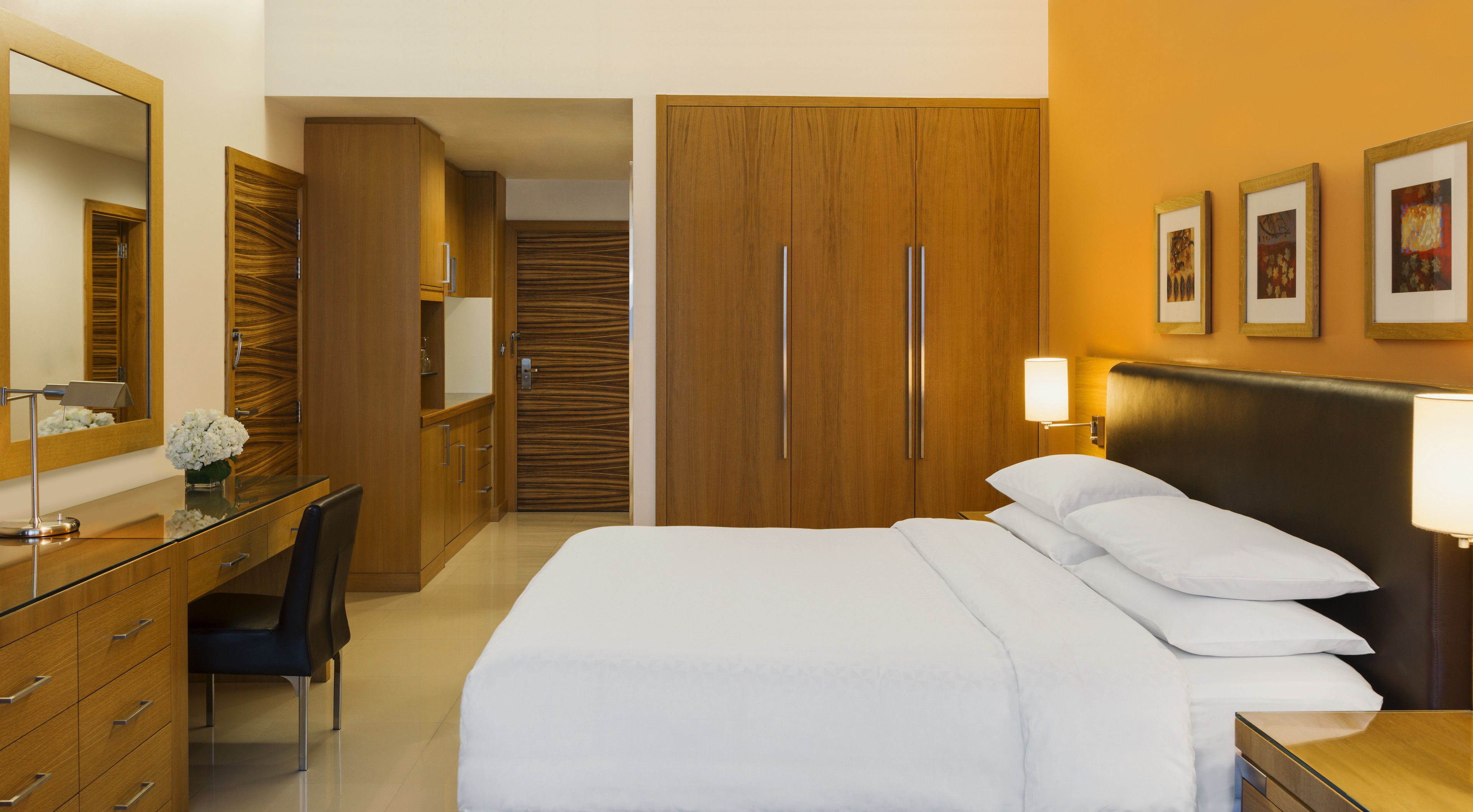 Hotellihuone, jossa on sänky, työpöytä tuolilla, vaatekaappi ja peili.
