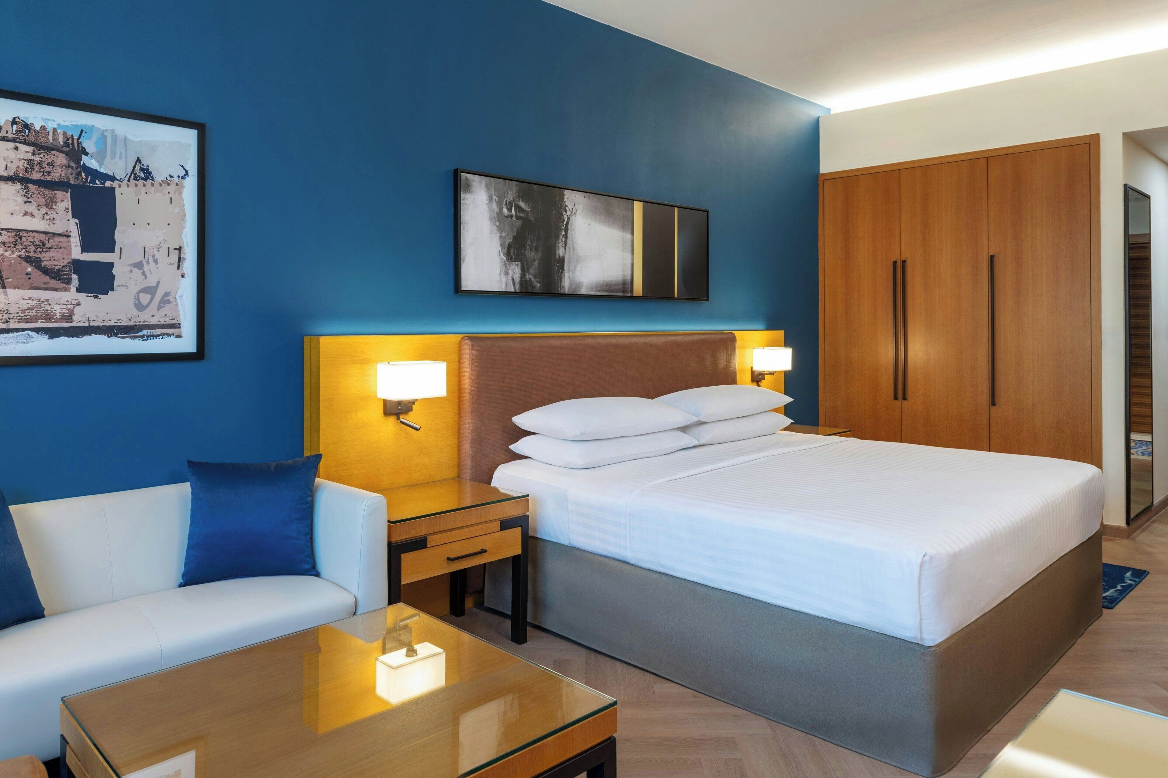 A hotel room with a bed, a sofa, a desk, and a wardrobe.