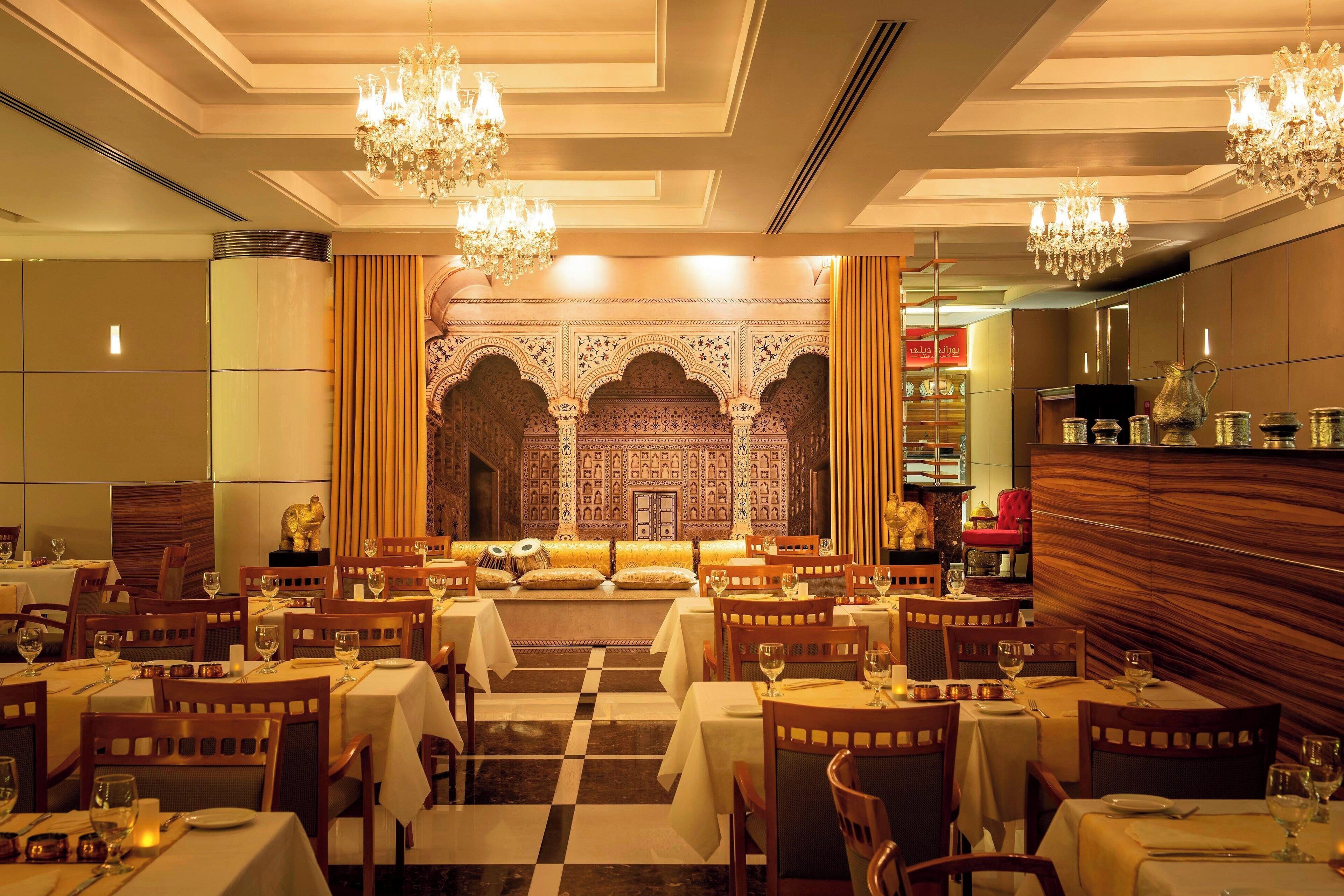 A restaurant with multiple tables, chandeliers, and a checkered floor.