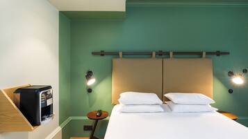 Een hotelkamer met een bed, nachtkastje en een koffieapparaat.