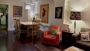 Un coin repas avec une table et des chaises en bois, un fauteuil rouge, un canapé et une lampe.