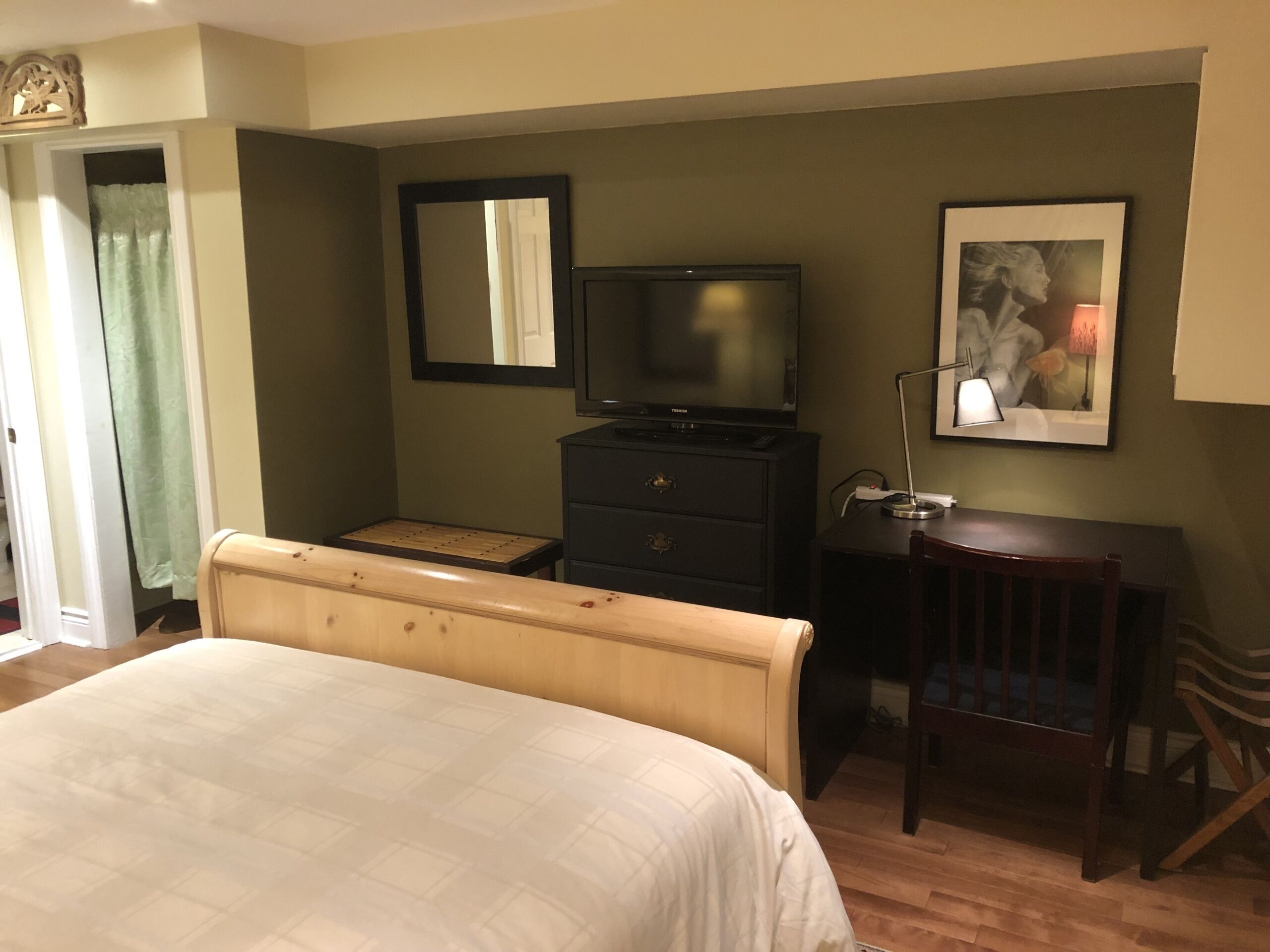 A hotel room with a bed, a TV, a desk, and a chair.