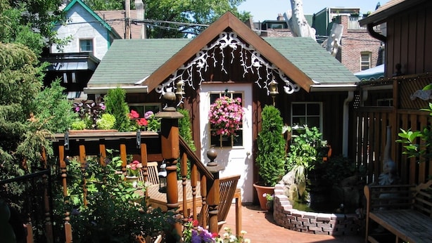 Une entrée de jardin accueillante, avec un escalier en bois, des plantes en pot et un chemin pavé de briques.