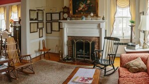 A traditional living room with a fireplace, wooden furniture, and a chandelier.