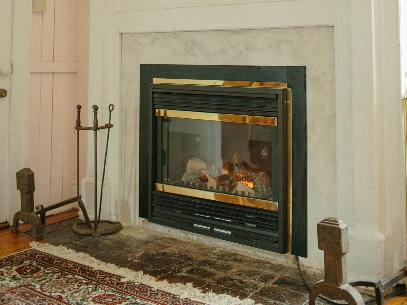 A fireplace with a glass front, a traditional design, and a rustic wooden floor.
