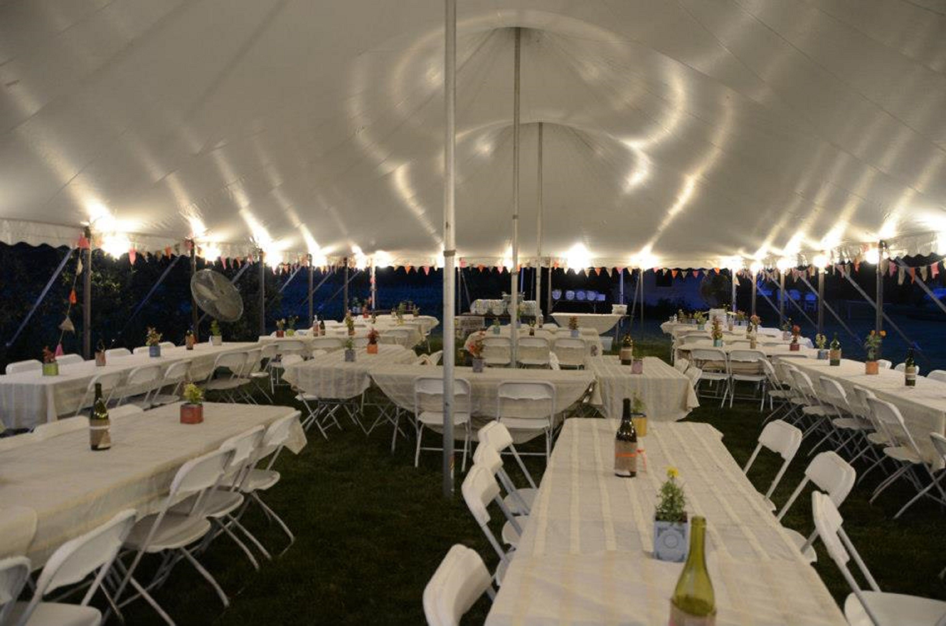 A tented event space with tables and chairs arranged for an event.