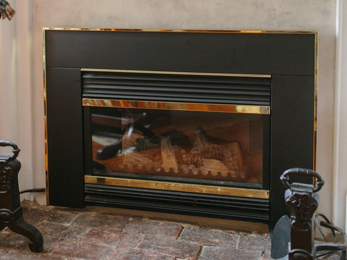A fireplace with a glass front, a stone hearth, and a metal frame.
