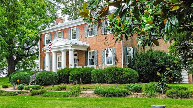 A brick building with a white porch, columns, and shutters.