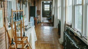 A narrow hallway with wooden flooring, a table with a white tablecloth, and various tools and equipment on the walls.