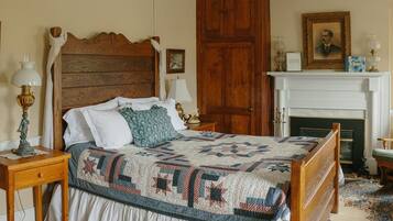 Une chambre à coucher de style traditionnel, avec un lit en bois, une cheminée blanche et un décor classique.
