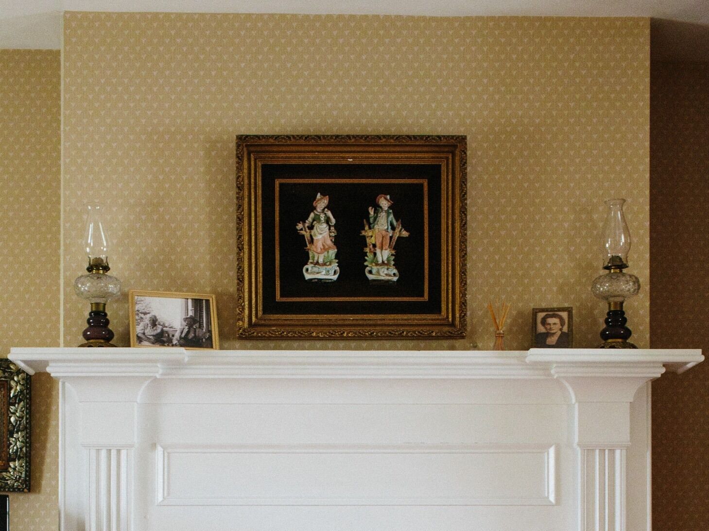 Une cheminée surmontée d’un tableau encadré, et de part et d’autre, deux lampes décoratives.