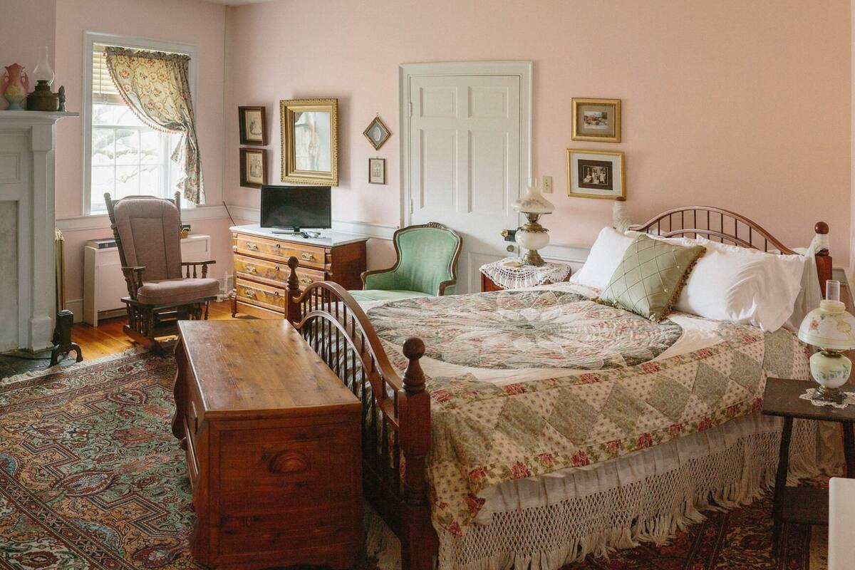 A traditional bedroom with a wooden bed, a desk, a chair, and a dresser.