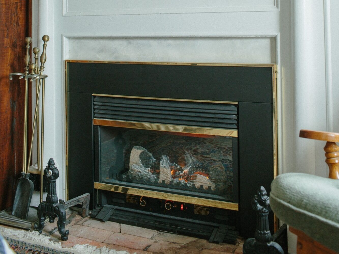 Una chimenea con una repisa negra y fuego a la vista. Sobre la repisa hay objetos decorativos como un candelabro y una pequeña estatua.